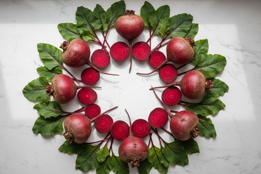 Vibrant fresh beet roots and sliced beets on a white marble surface